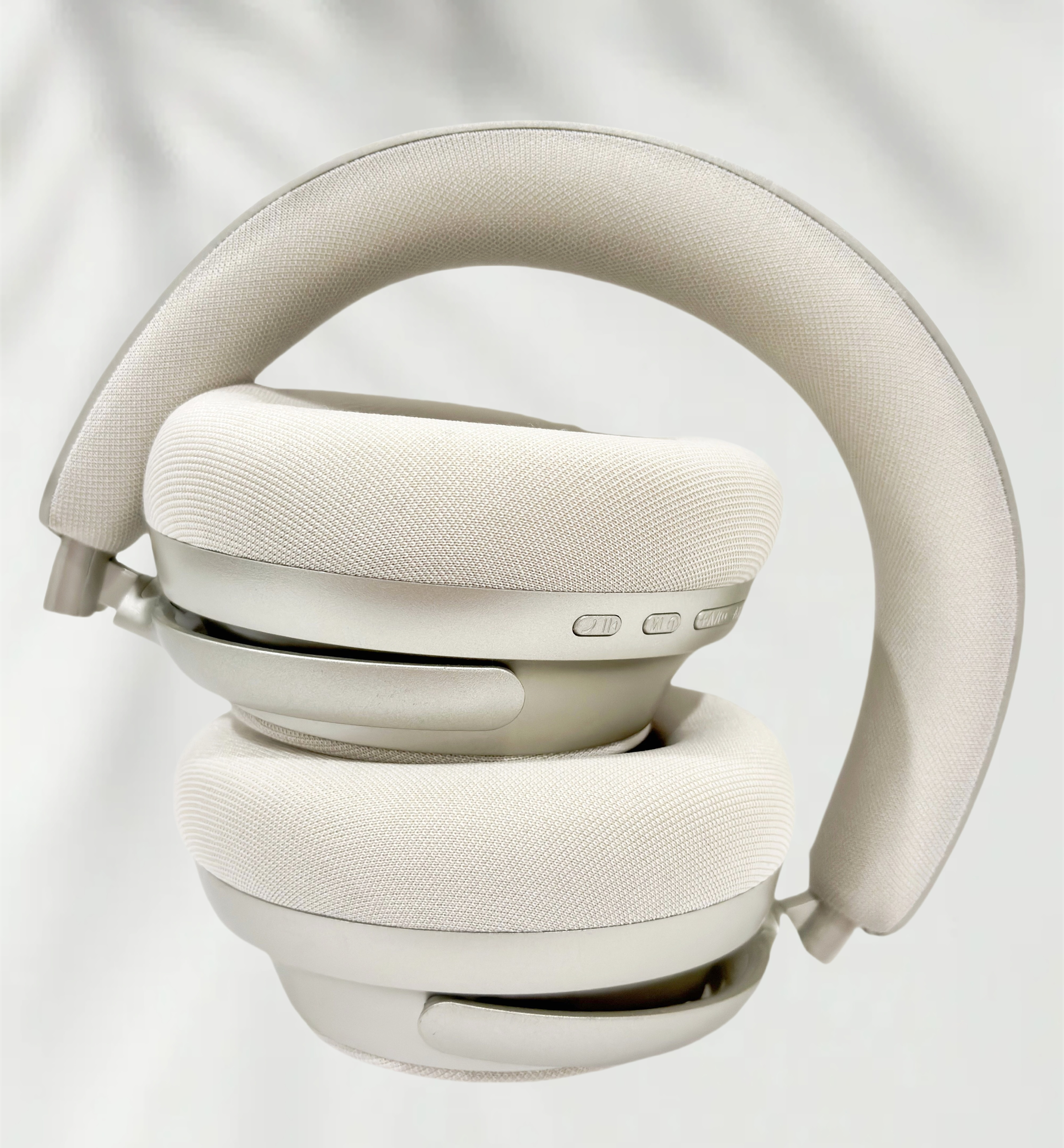 Auriculares plegados, mostrando las orejeras y la diadema. Los auriculares son de color gris claro.