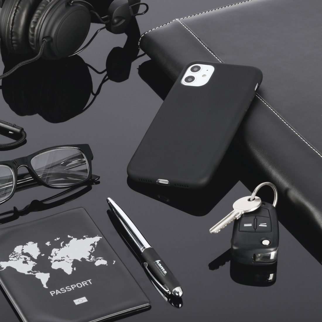 Ein Schreibtisch mit Zubehör. Telefon, Brille, Reisepass, Kopfhörer, Stift, Schlüssel und Notizbuch.