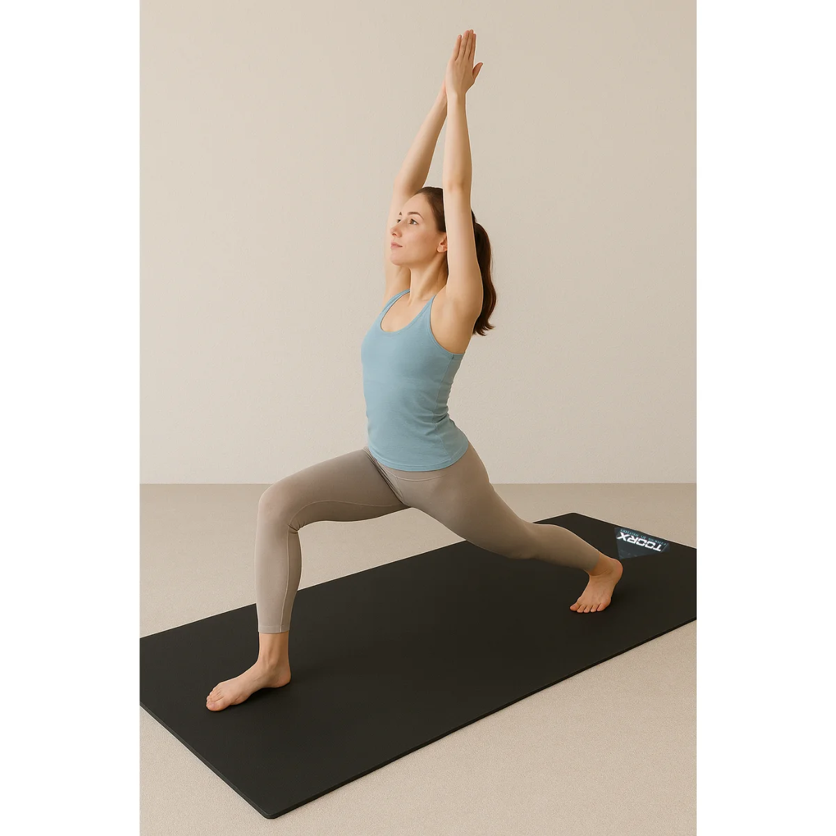 Vrouw in yoga pose, armen omhoog, op een zwarte mat. Beige legging en tanktop. Achtergrond is neutraal.