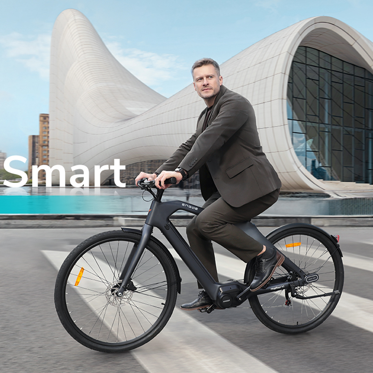 Mężczyzna na czarnym rowerze, przed nowoczesnym budynkiem z elementem wodnym. Słowo "Smart" po lewej.