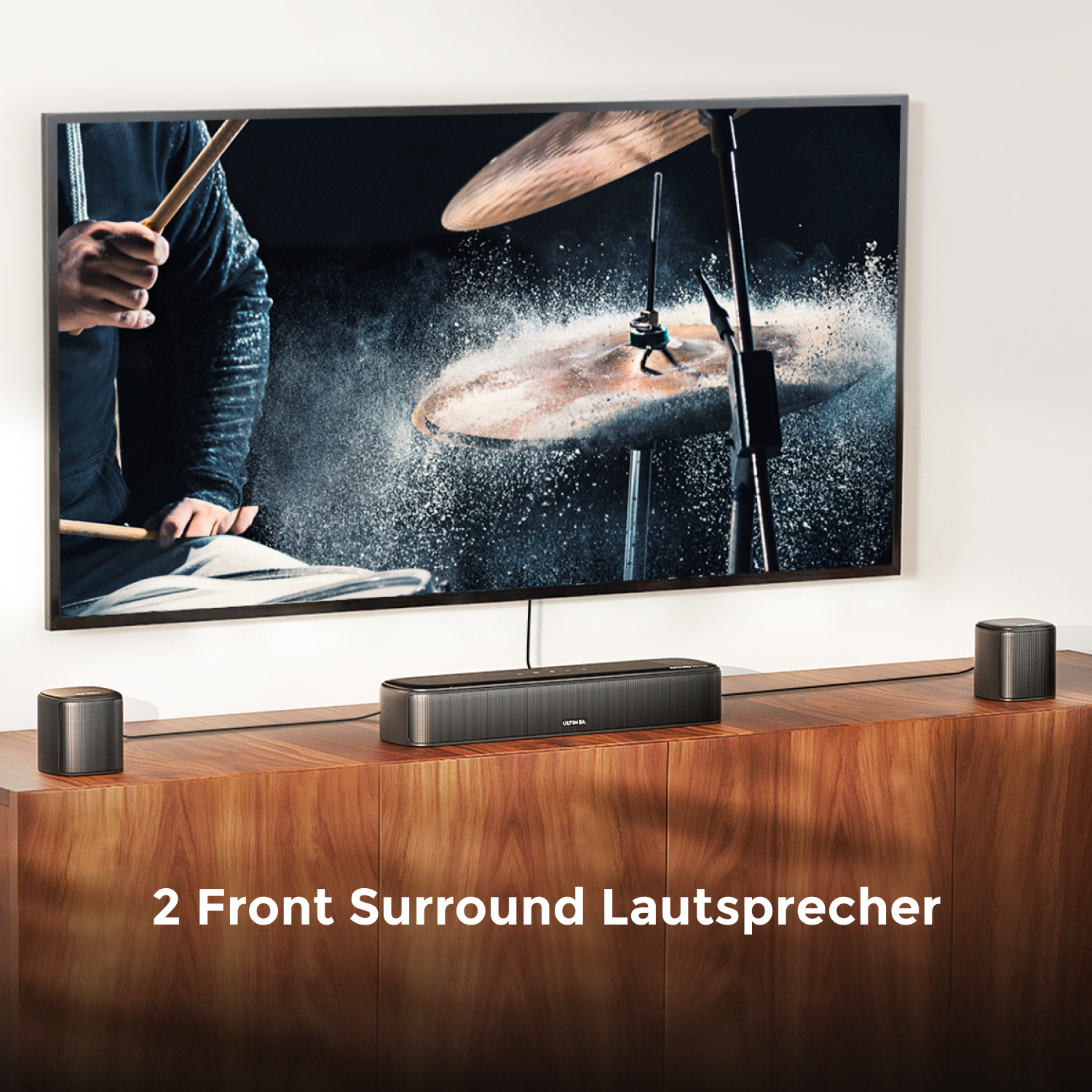 Un televisore è su un mobile in legno. Una soundbar è sotto con due piccoli altoparlanti. Lo sfondo è bianco.