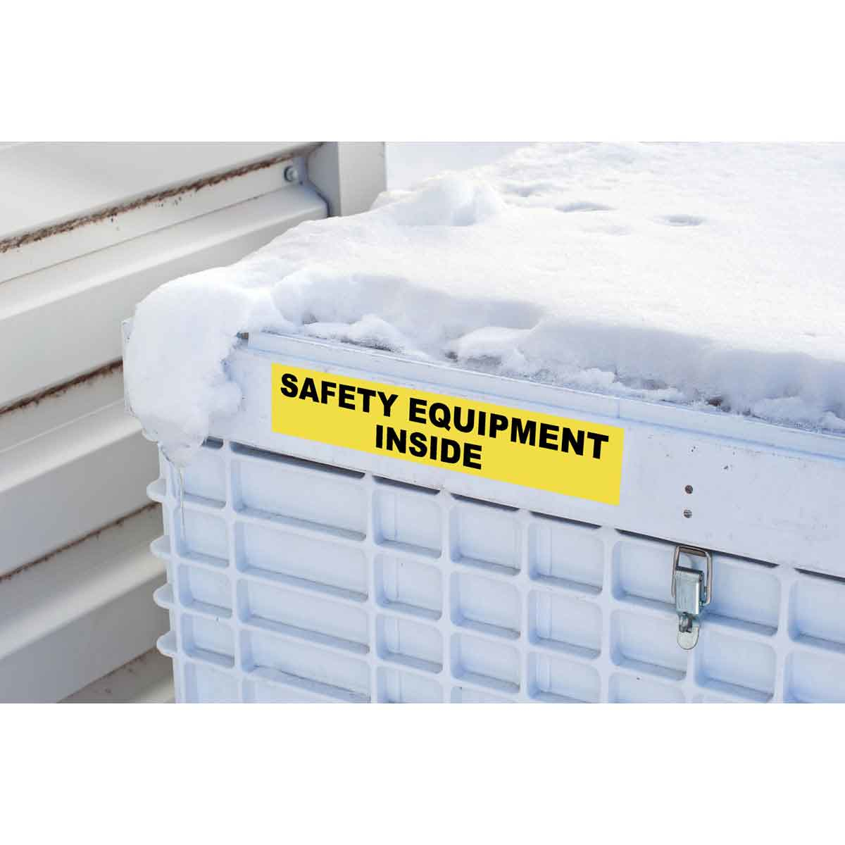 Un cartello giallo su un contenitore bianco coperto di neve. Il cartello dice 'ATTREZZATURE DI SICUREZZA ALL'INTERNO'.
