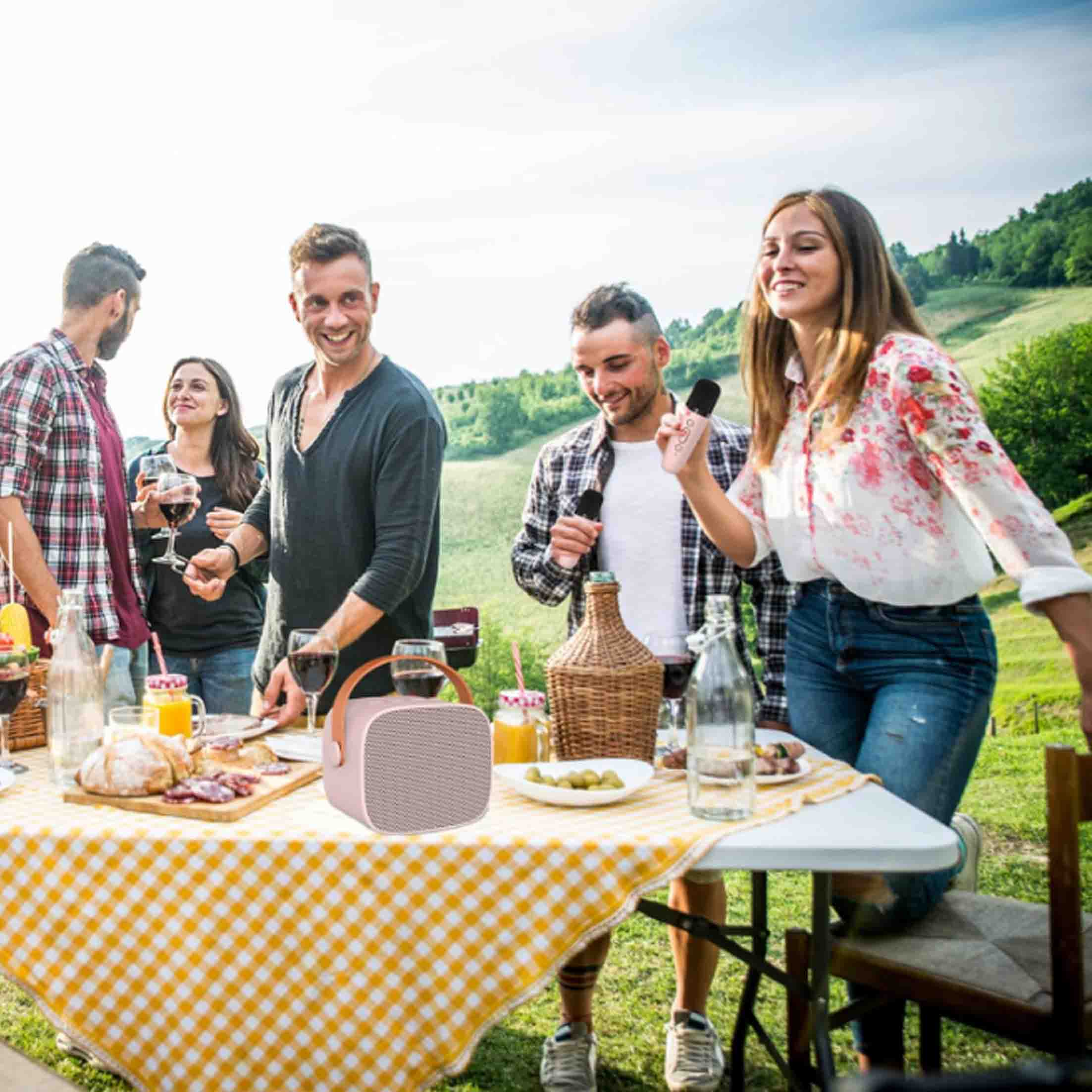 Leute an einem Picknicktisch mit Essen und Getränken, mit einem rosa Lautsprecher auf dem Tisch.