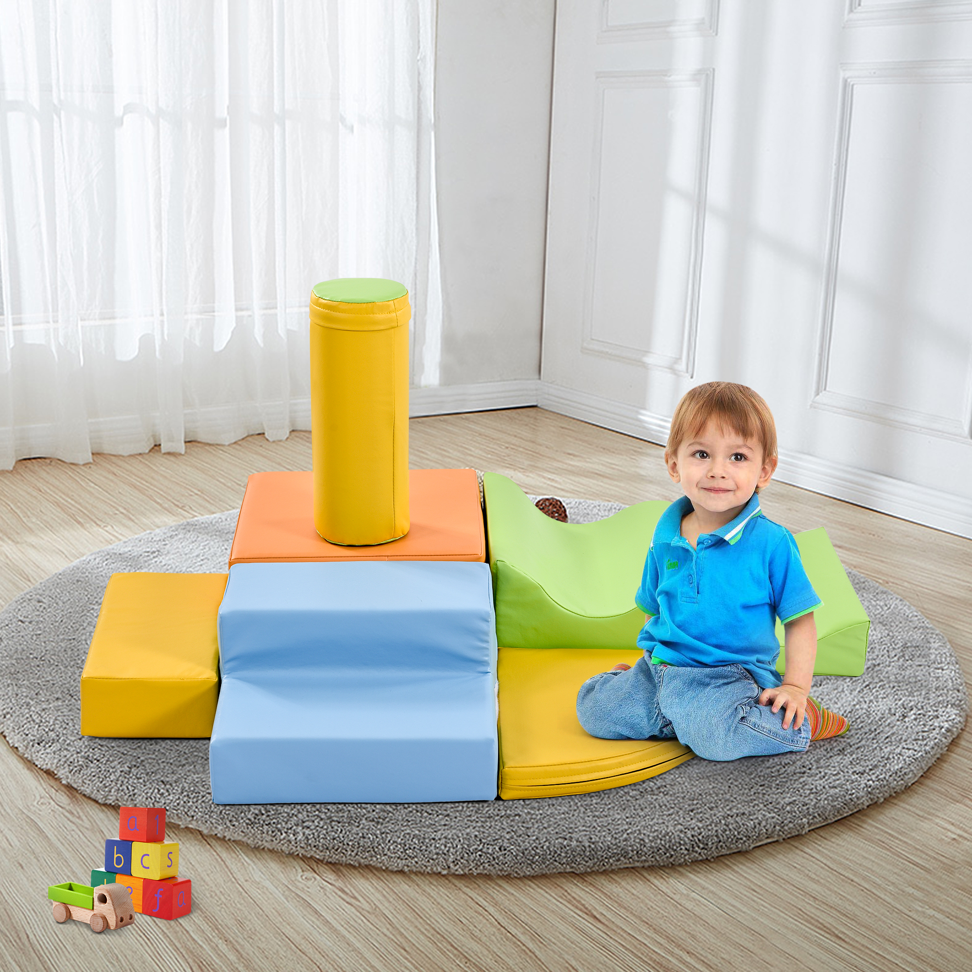 Ein kleiner Junge sitzt vor bunten Schaumstoffblöcken und lächelt in die Kamera.