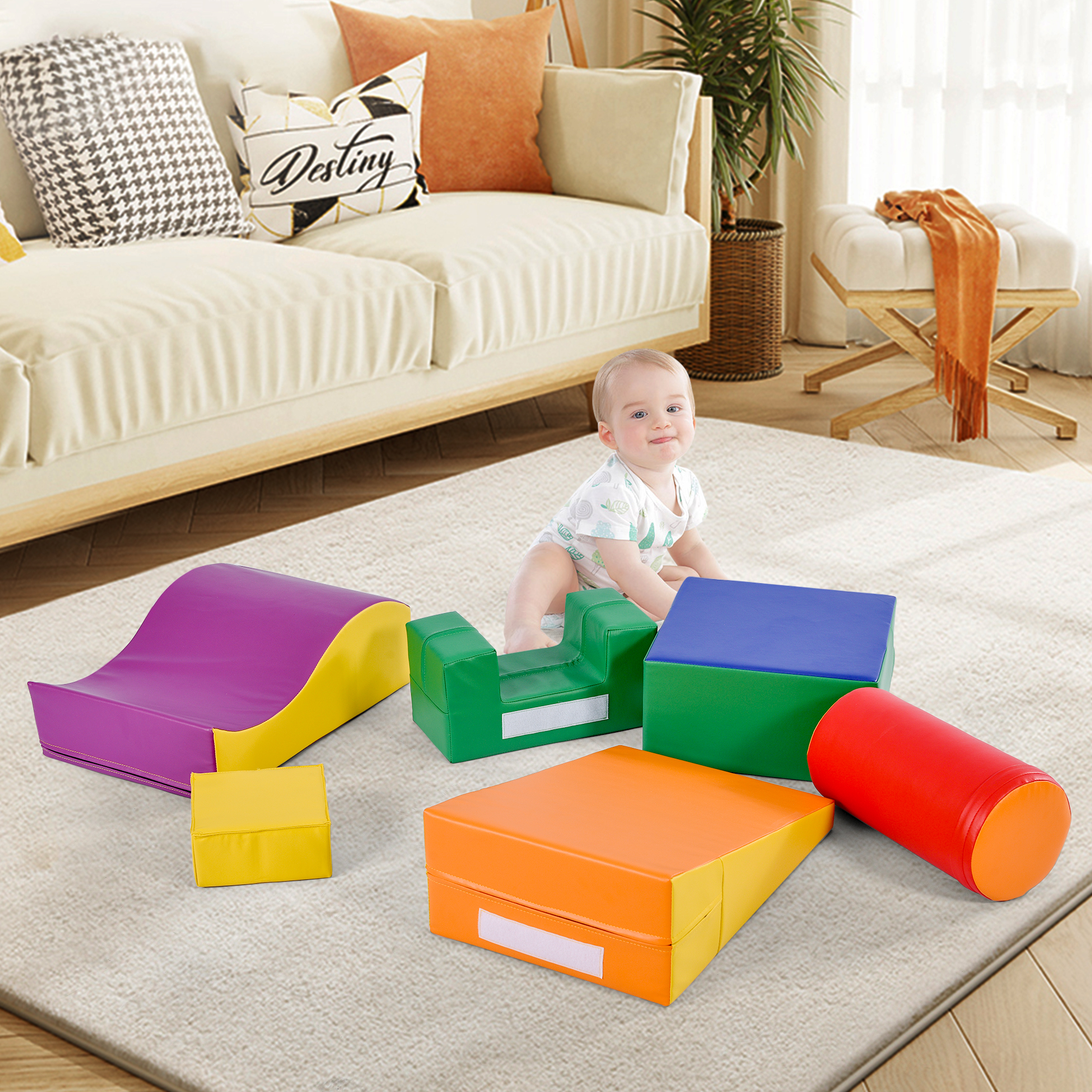 Ein Baby sitzt inmitten bunter Schaumstoff-Spielblöcke. Im Hintergrund sind ein Sofa und ein Hocker zu sehen.