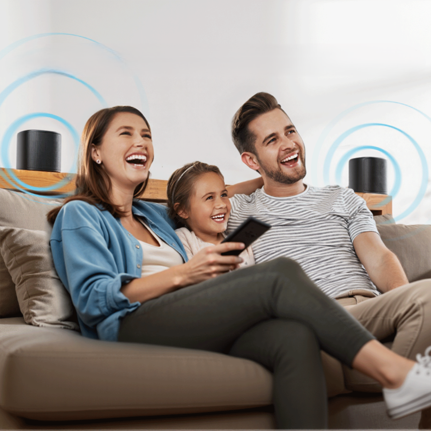 Rodzina śmieje się na kanapie, oglądając telewizję z głośnikami po obu stronach.