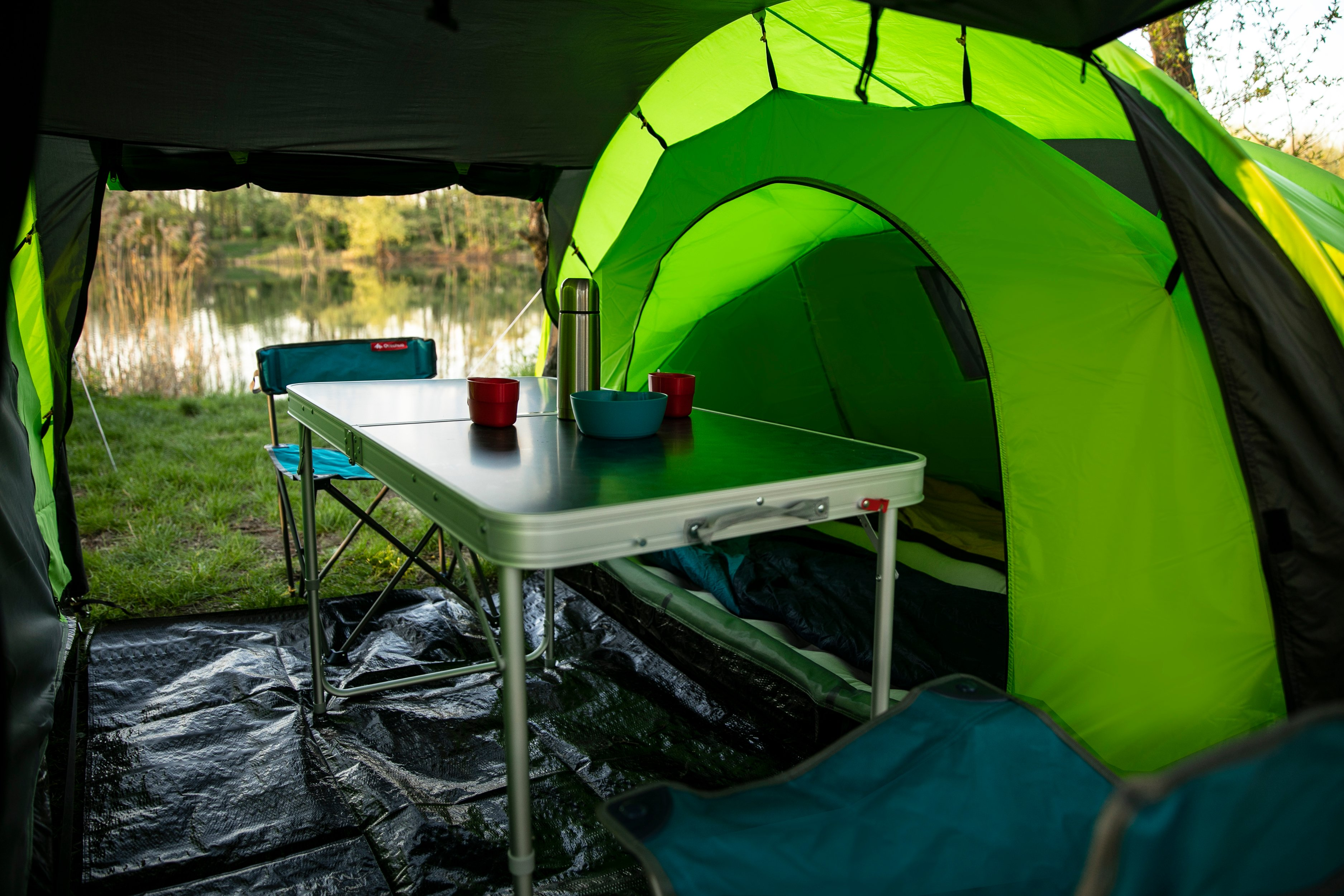 Im Zelt, Campingtisch und Ausrüstung. See durch die Tür sichtbar.