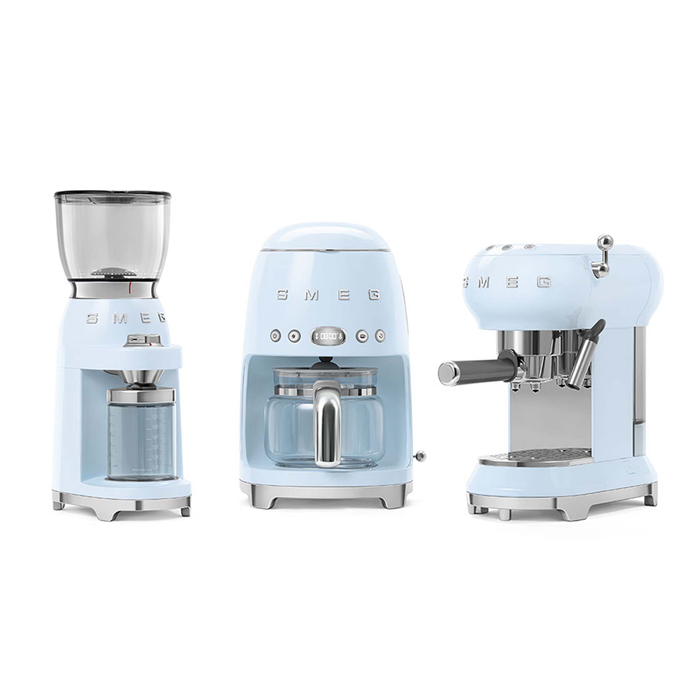 Tre macchine da caffè SMEG azzurre: macinacaffè, caffettiera, macchina per espresso. Sfondo bianco.