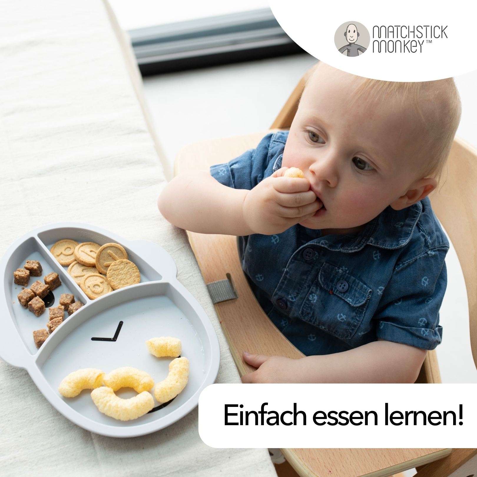Baby isst von einem grauen Affenteller mit Essen, in einem Hochstuhl.