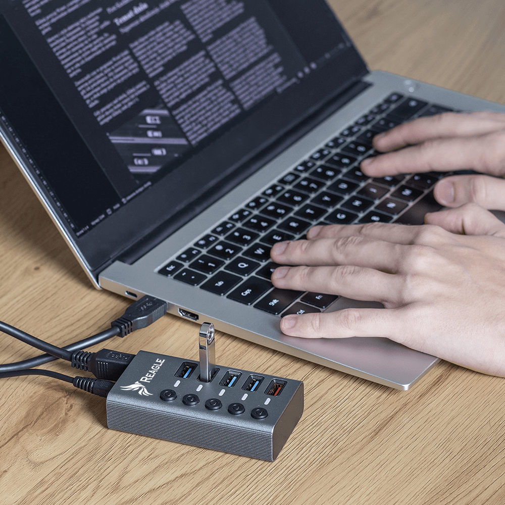 Ręce piszące na klawiaturze laptopa, z hubem USB i dyskiem flash.