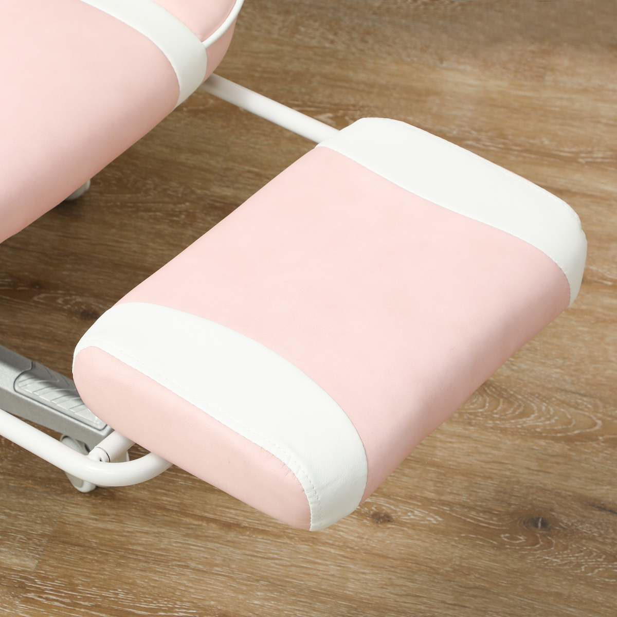 Nahaufnahme einer rosa Fußstütze eines Stuhls, mit Weiß verziert, auf Holzfußboden.