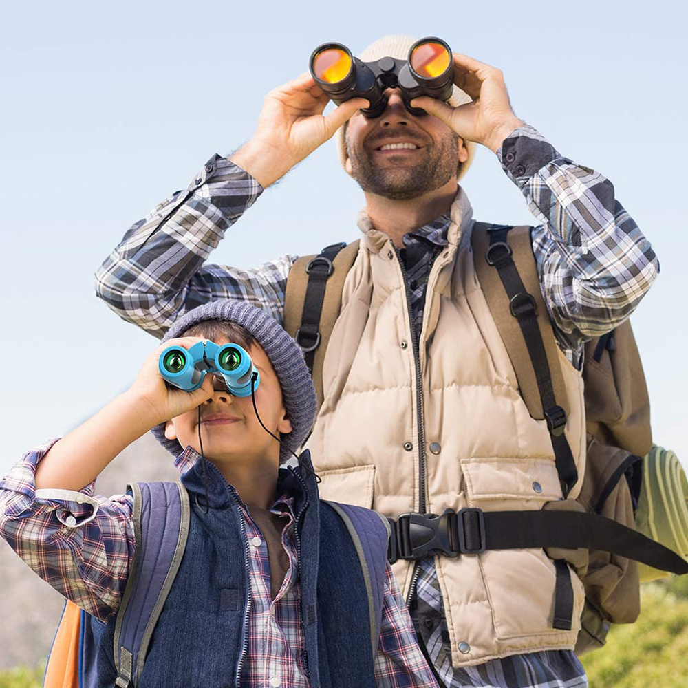 Ein Vater und sein Sohn schauen durch ein Fernglas. Der Vater trägt eine beige Weste. Der Hintergrund ist sonnig.
