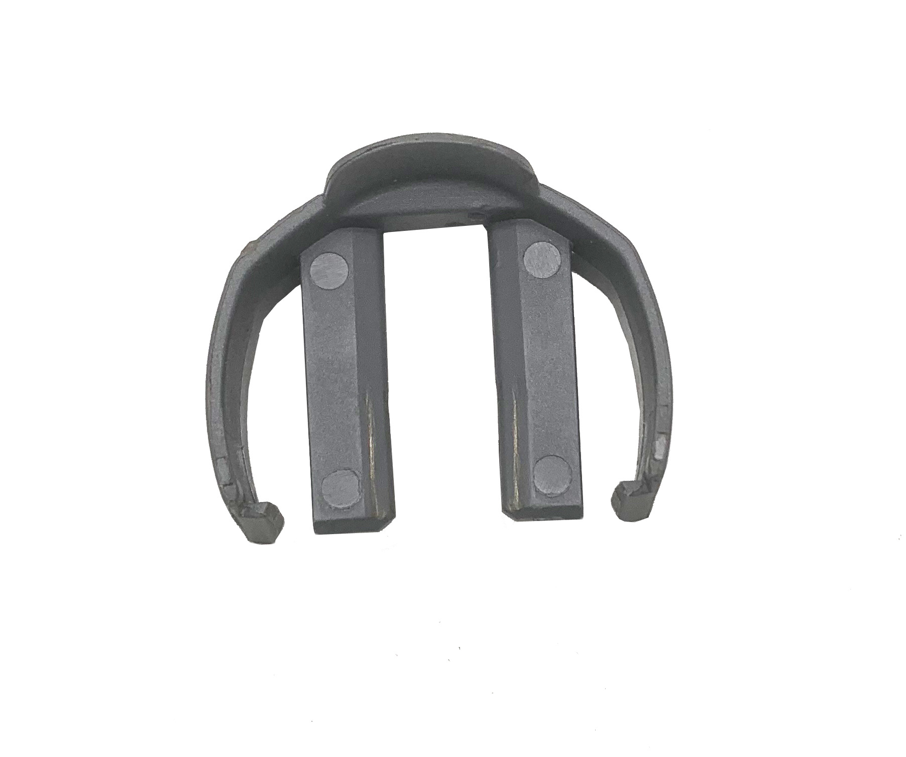 Ciemnoszary metalowy obiekt przypominający klips z dwoma prostokątnymi szczelinami pośrodku, na białym tle.