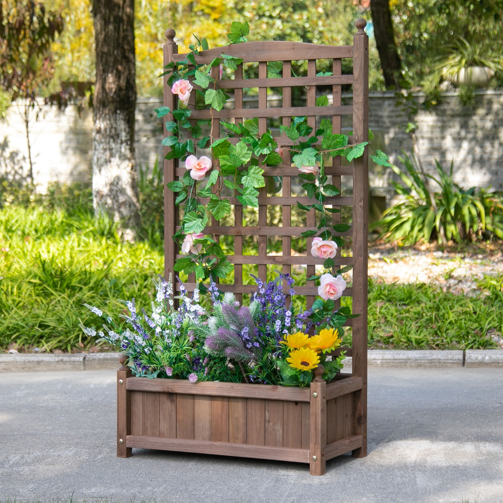 Ein Holzpflanzer mit Spalier, Blumen und Weinreben. Bäume sind im Hintergrund.