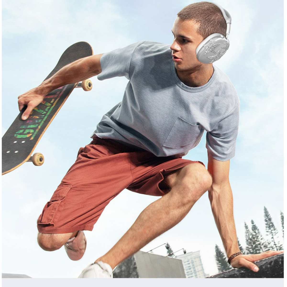 Junger Mann auf Skateboard, Kopfhörer tragend, in der Luft, vor blauem Himmel.