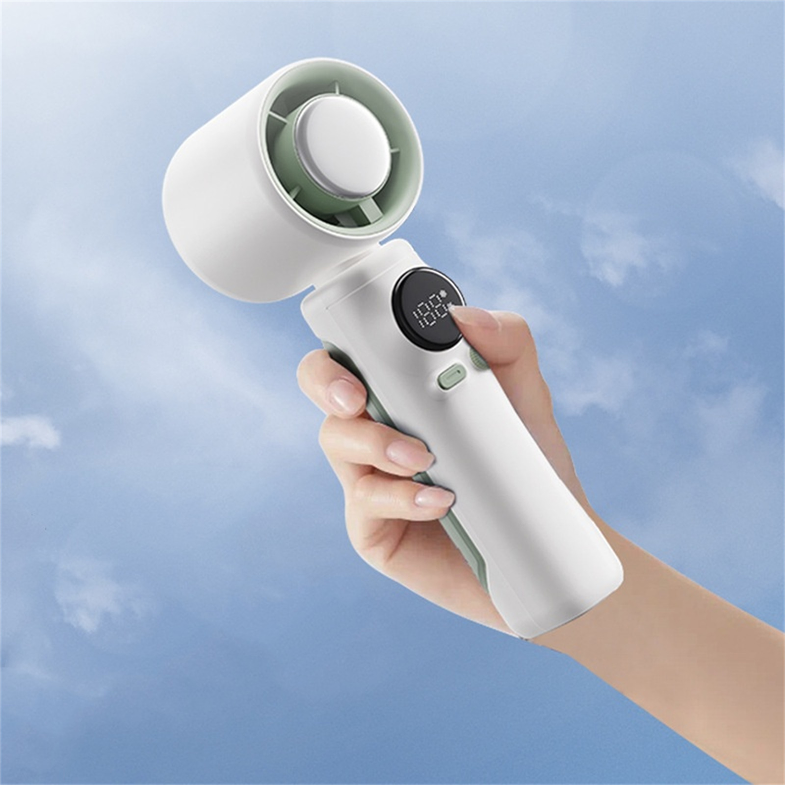 Eine Hand hält einen weißen und grünen tragbaren Ventilator vor blauem Himmel.