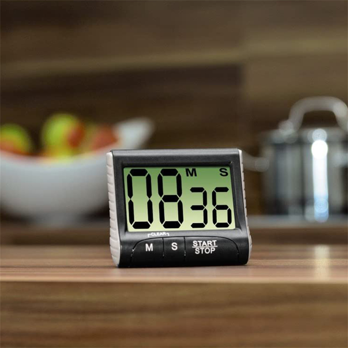 Digitaler Timer mit schwarzem Rahmen. Zeigt '08:36'. Knöpfe: M, S, START/STOP. Holzoberfläche.