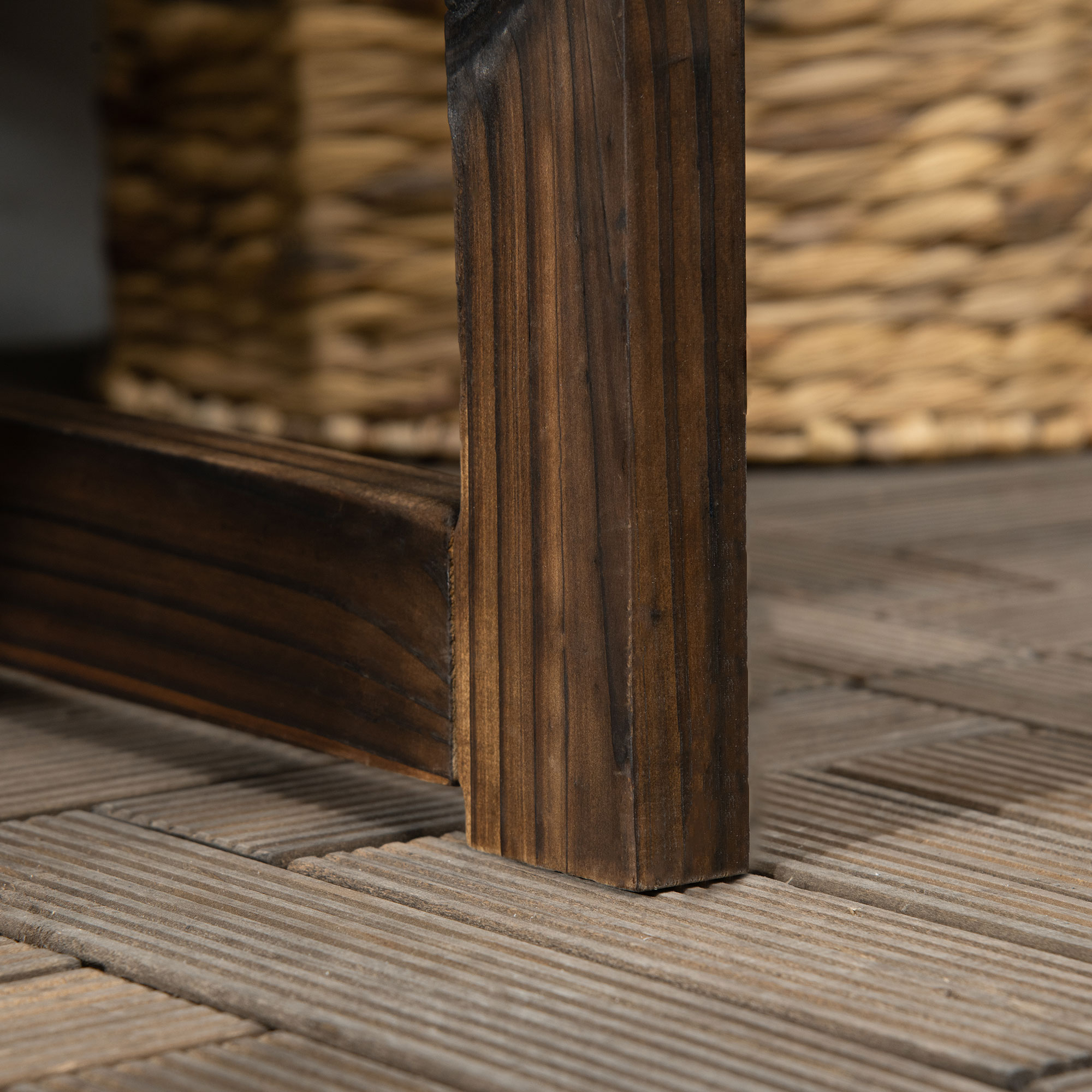 Nahaufnahme eines Holzbein auf Holzterrasse. Ein Weidenkorb im Hintergrund.