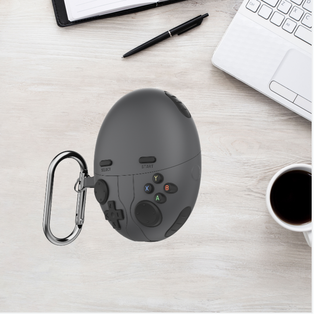 Un controller di gioco grigio a forma di uovo con pulsanti e un moschettone argentato su una superficie in legno.