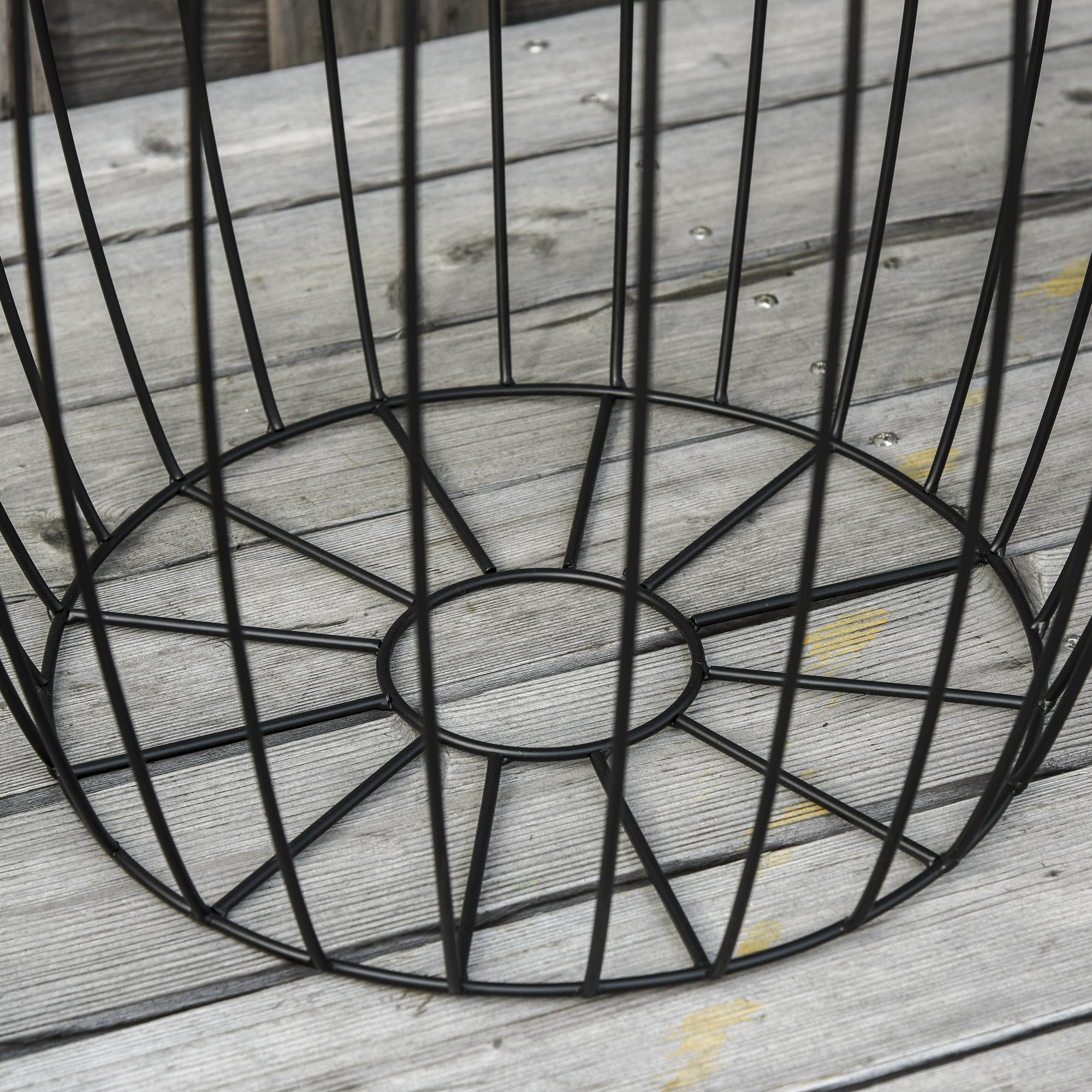 Nahaufnahme des Sockels eines schwarzen Metall-Beistelltischs mit kreisförmigem Design auf Holz.