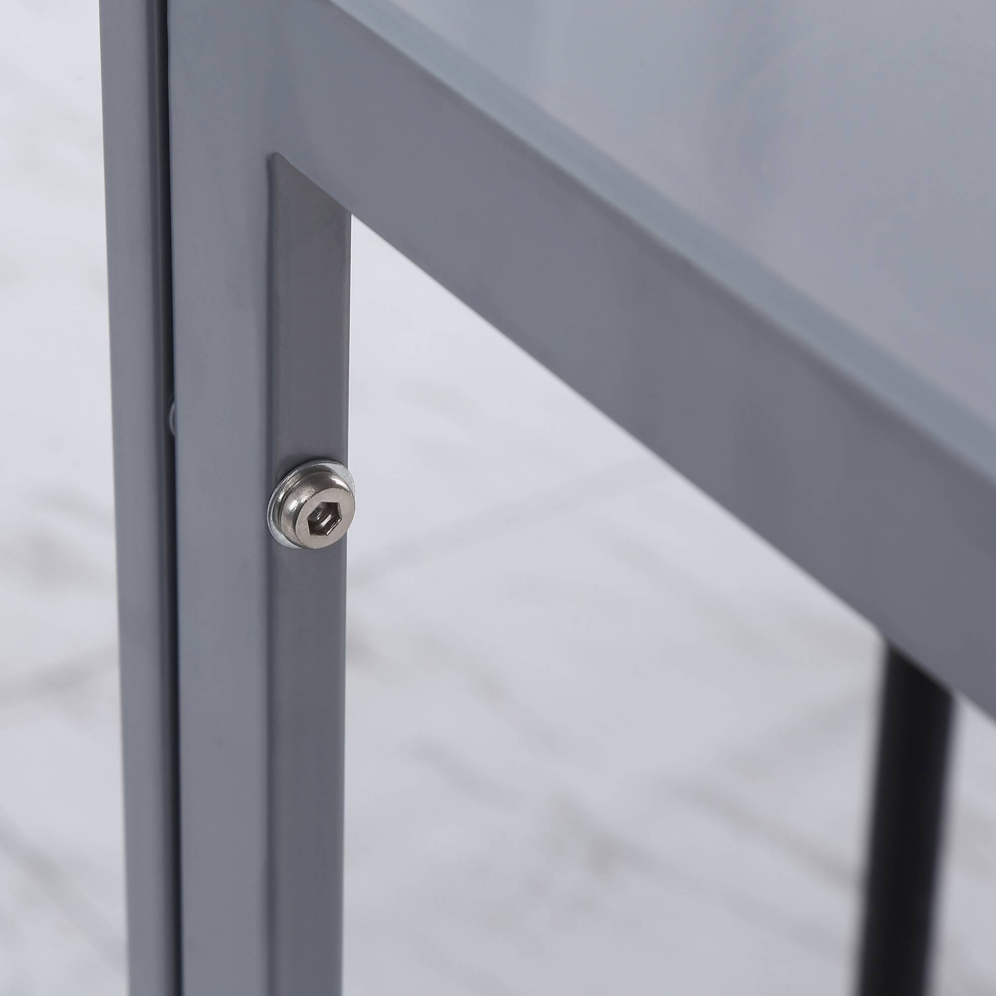Nahaufnahme einer Metallrahmenverbindung mit einer Schraube, vor einem hellen Holzboden.