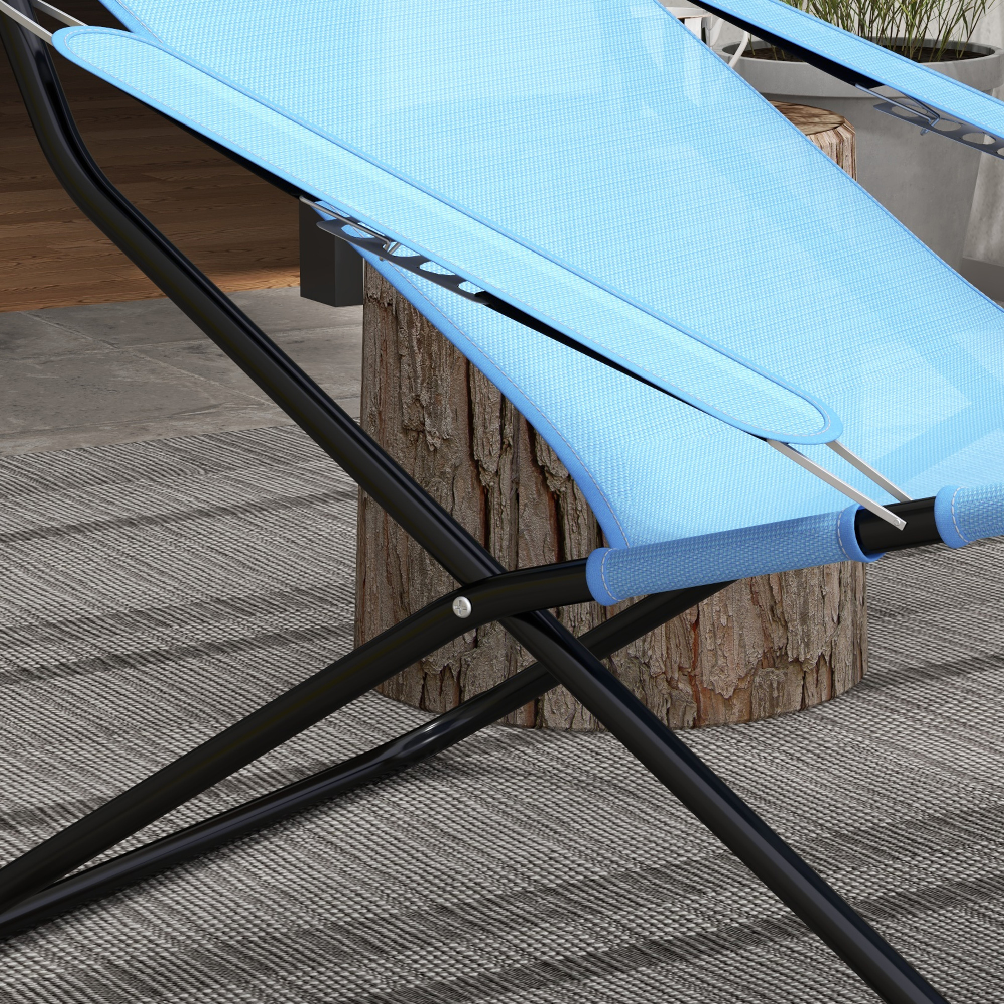 Nahaufnahme eines blauen Klappstuhls. Der Stuhl steht auf einem Teppich, im Hintergrund ein Holztisch.