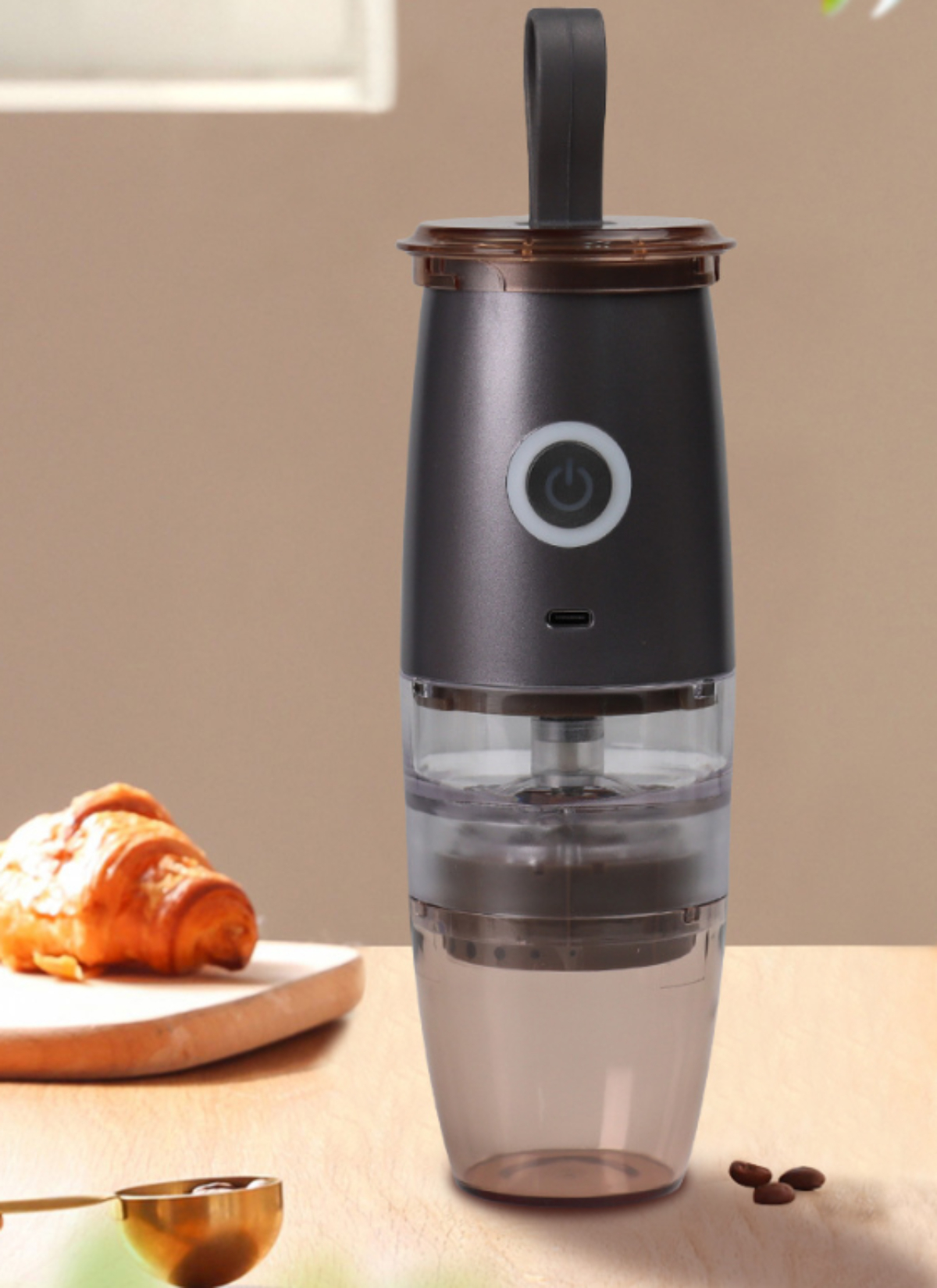 Kaffeemaschine, schwarz und transparent. Mit Griff. Kaffeebohnen und Croissant auf dem Tisch.