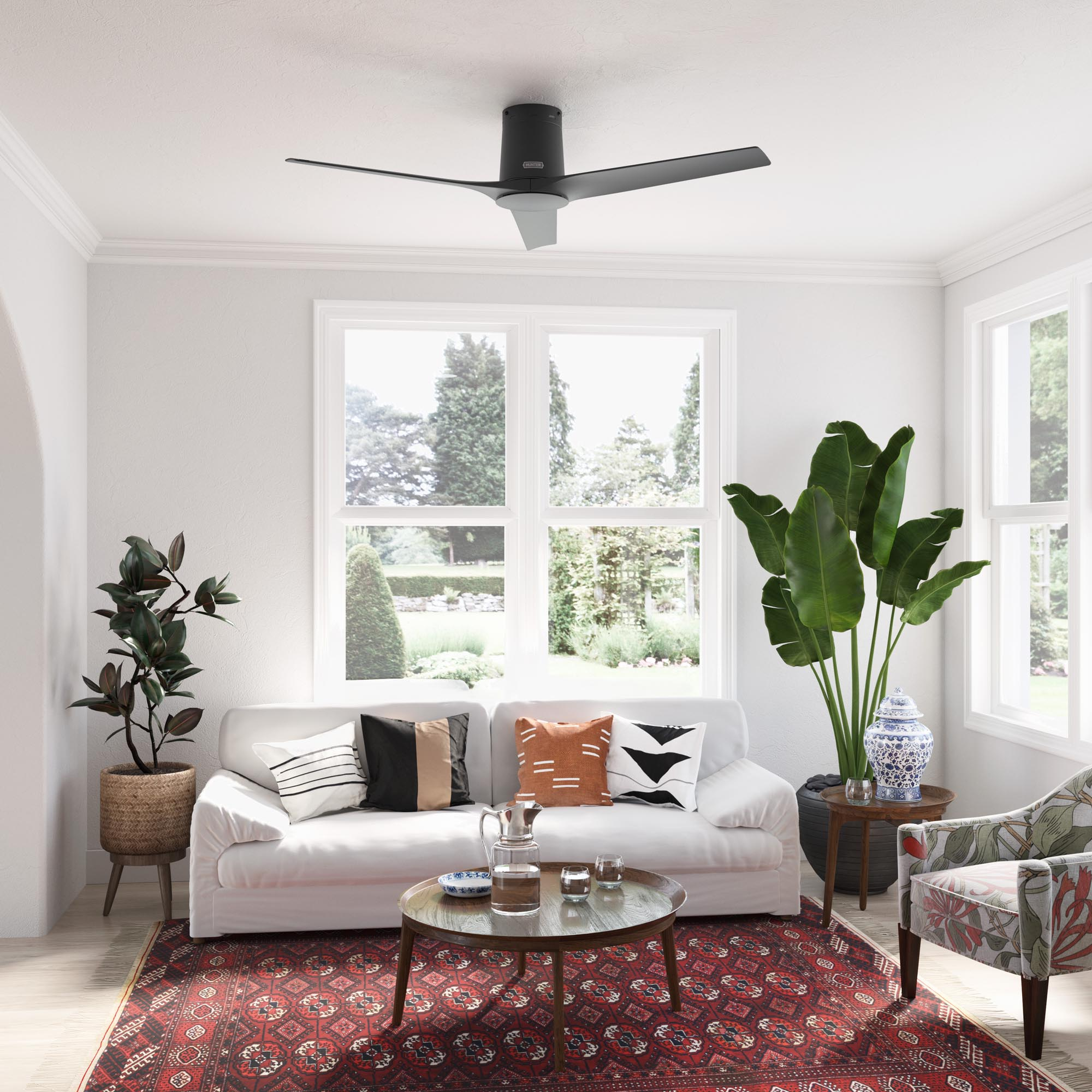 Wohnzimmer mit weißem Sofa, Teppich, Pflanzen, Deckenventilator und Kunst. Heller, luftiger Raum.