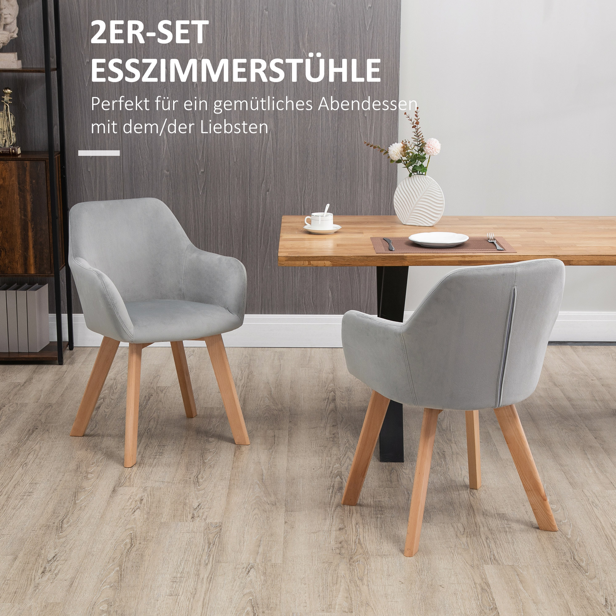 Zwei graue Sessel mit Holzbeinen und ein Tisch mit Gegenständen darauf.