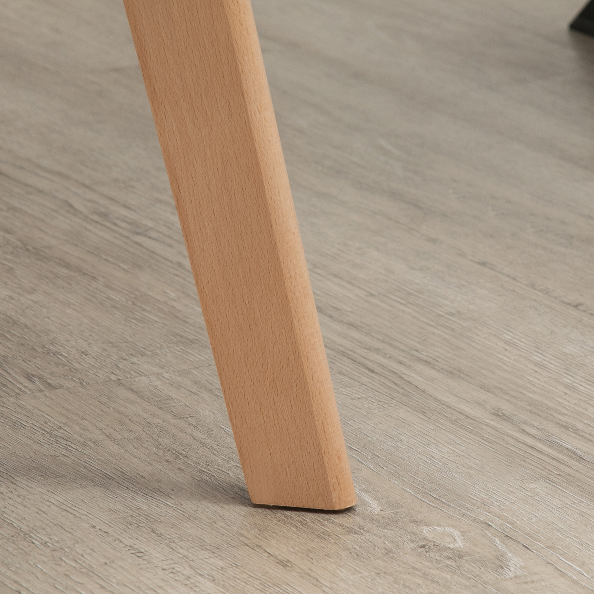 Holzstuhlbein auf hellem Holzboden. Das Bein hat eine hellbraune Farbe.