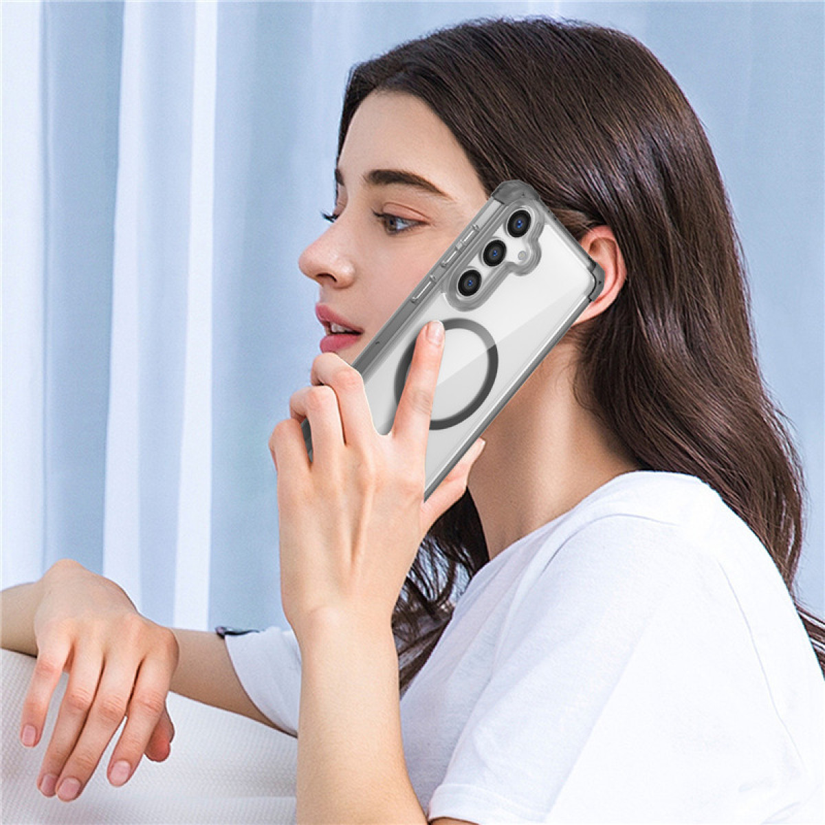 Donna che tiene un telefono in una custodia trasparente all'orecchio. Il telefono è bianco.