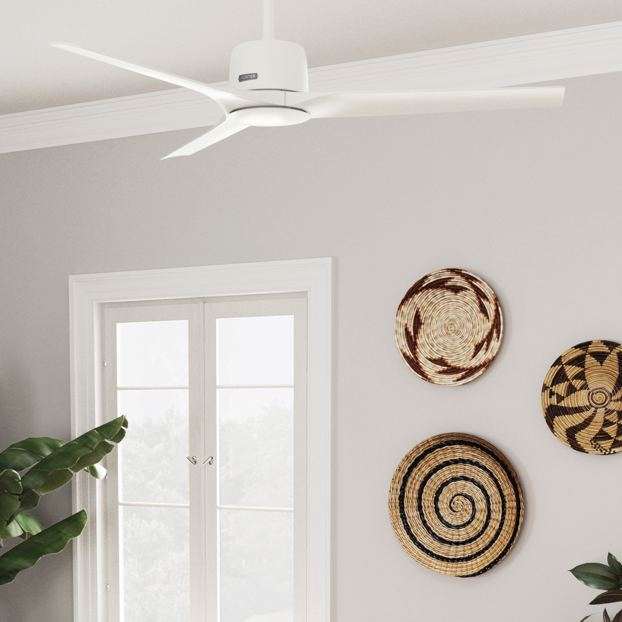 Weißer Deckenventilator mit 5 Flügeln. Hellgraue Wand, Fenster und Dekor im Hintergrund.