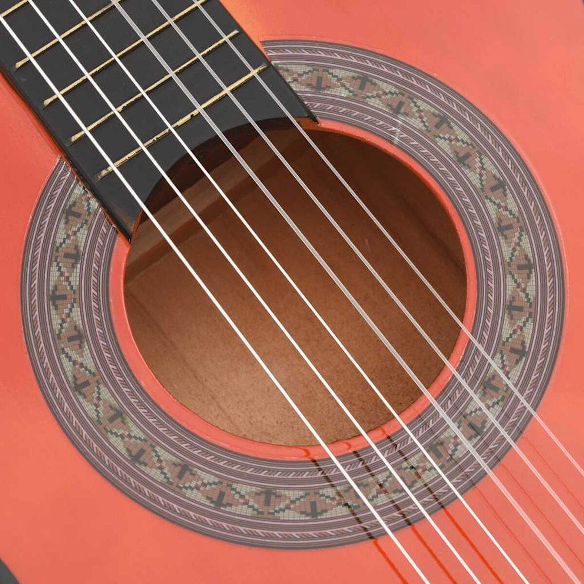 Nahaufnahme von Schallloch und Saiten einer roten Gitarre. Das Schallloch hat ein Muster.