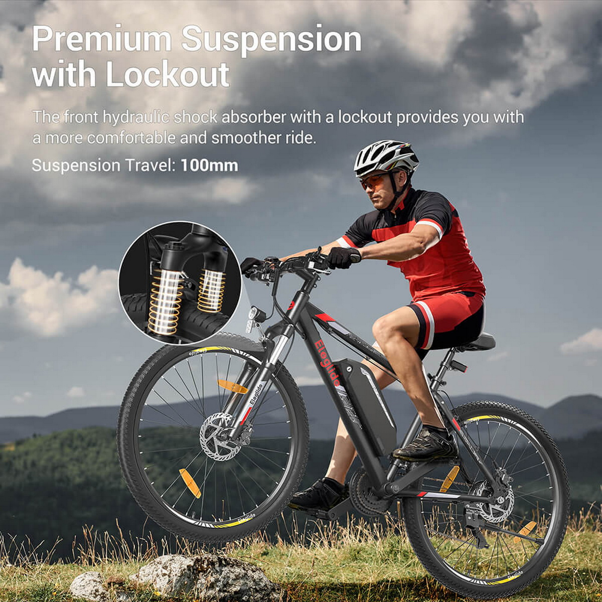 Mężczyzna jadący czarnym rowerem górskim na trawiastym polu.