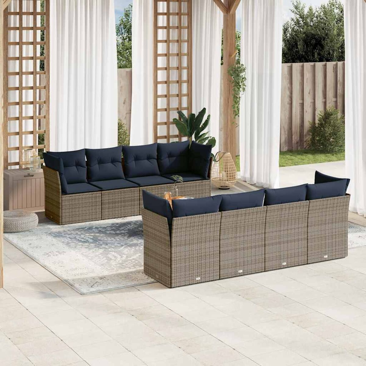Juego de asientos para exteriores en un patio. Tiene un sofá y sillones de mimbre marrón, con cojines azules.