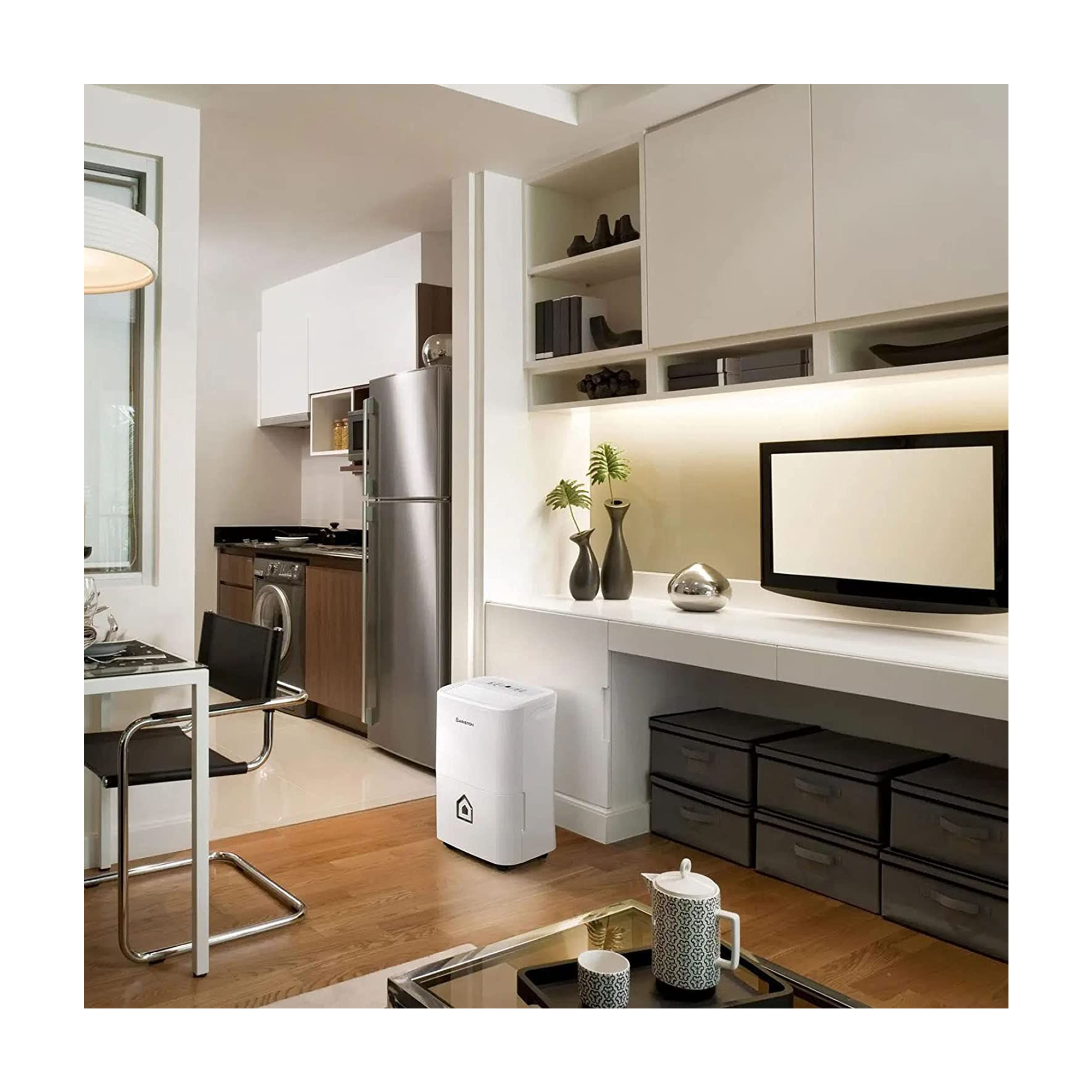 Sala de estar con deshumidificador, escritorio y electrodomésticos. Muebles blancos, piso de madera.