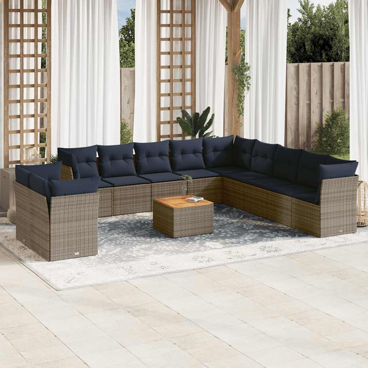 Set da patio esterno con mobili in vimini marrone e cuscini blu. Un tavolino di legno al centro.