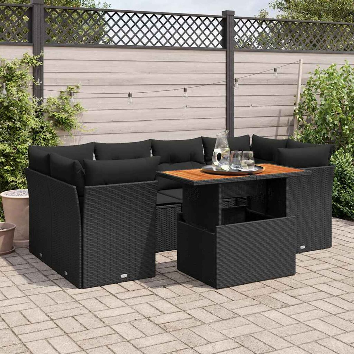 Set di mobili da esterno in vimini nero con cuscini e tavolo in legno.