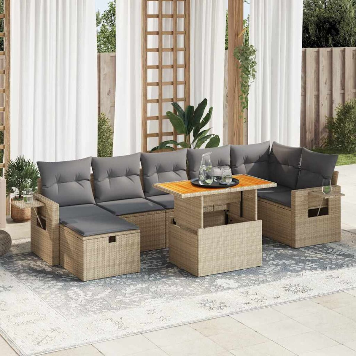 Un set di sedute da esterno con telai beige, cuscini grigi e un tavolo con piano sollevabile. Tende e piante.