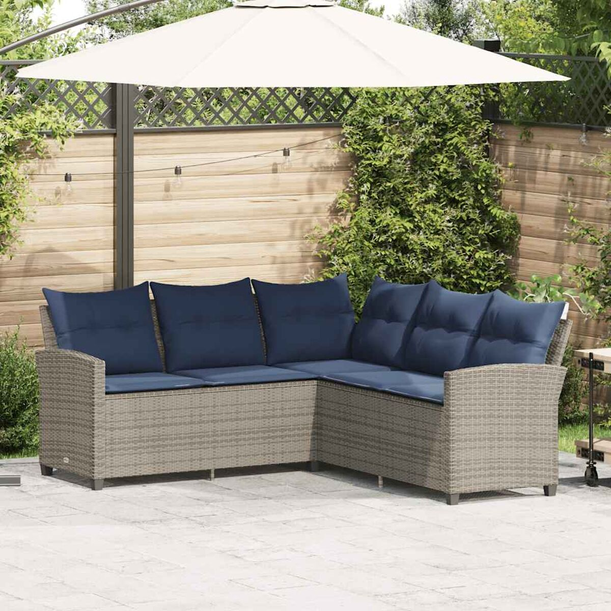 Divano angolare da esterno con cuscini blu, un ombrello bianco e uno sfondo di giardino.