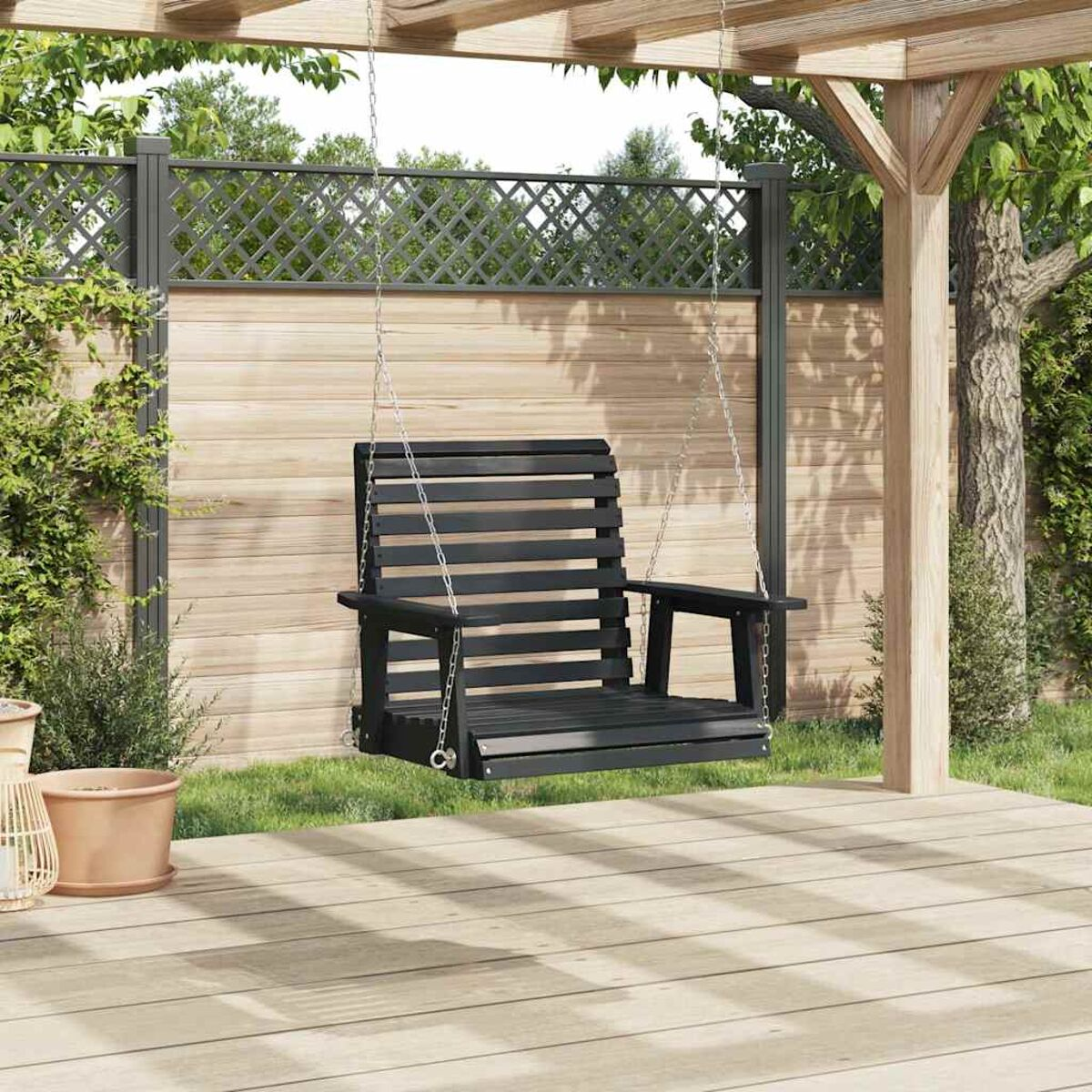 Eine schwarze Holzschaukel, die an einer Pergola hängt. Der Hintergrund umfasst einen Zaun und Bäume.