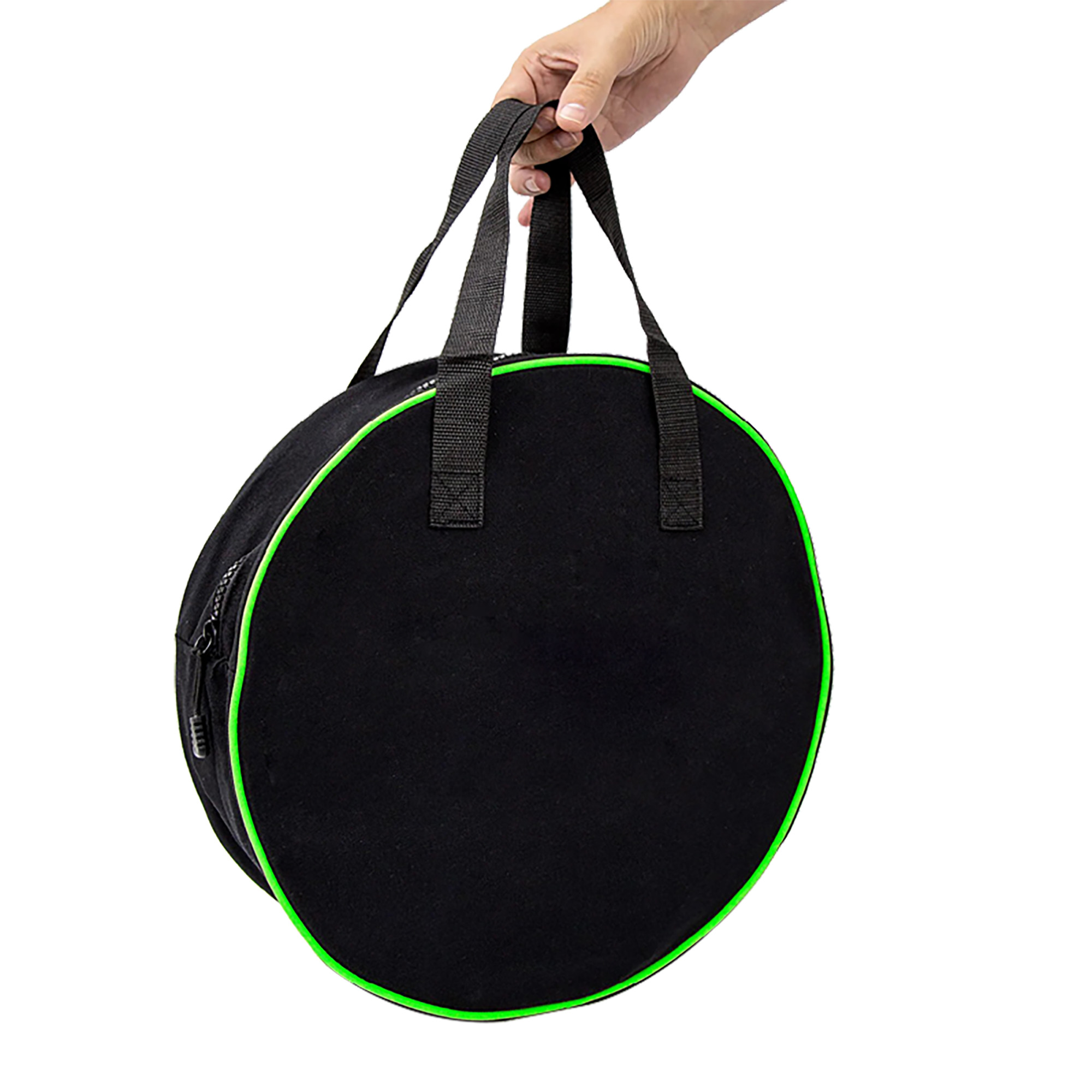 Una mano sostiene una bolsa redonda negra con ribete verde y asas, sobre un fondo blanco.