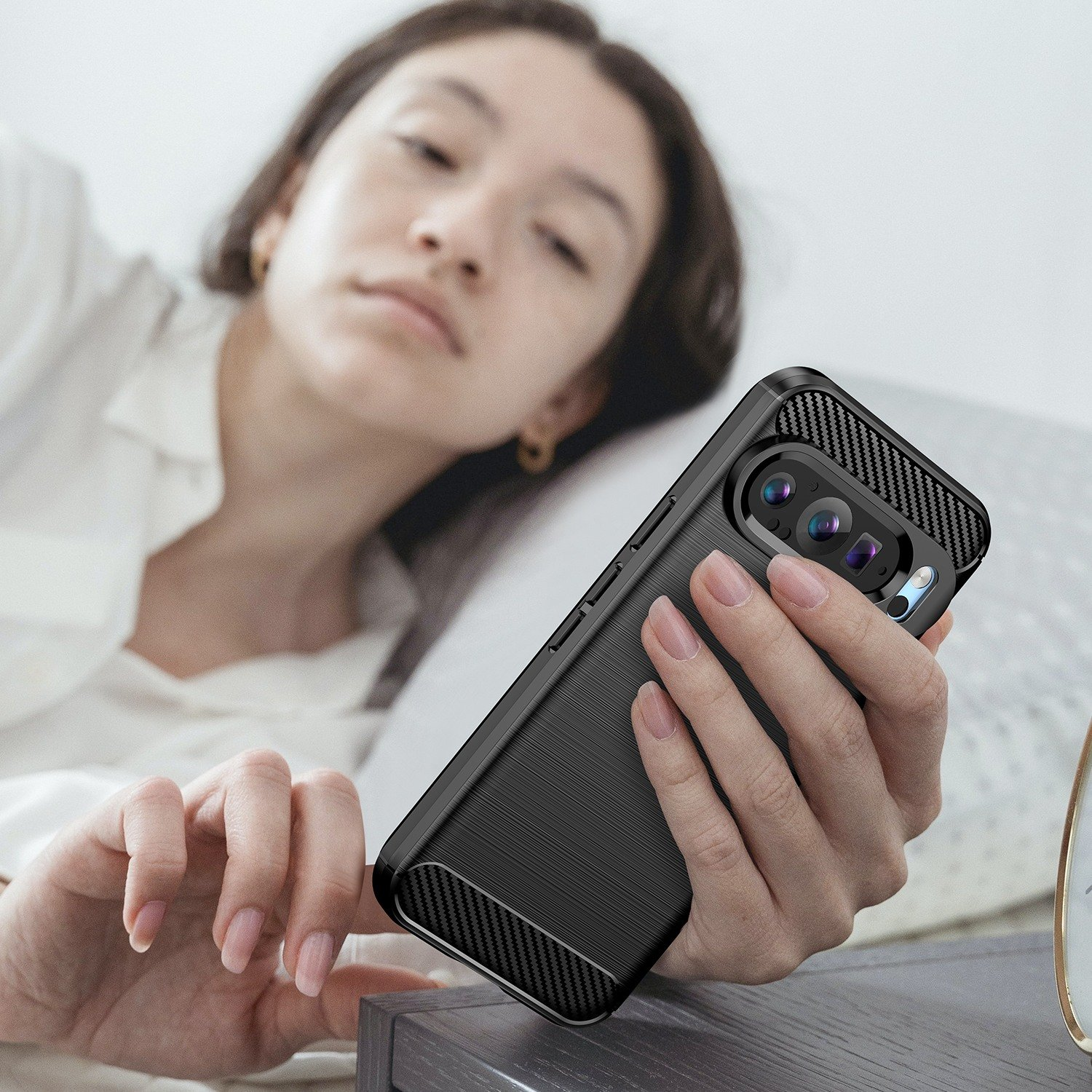 Una mujer en la cama sosteniendo un teléfono con una funda negra.