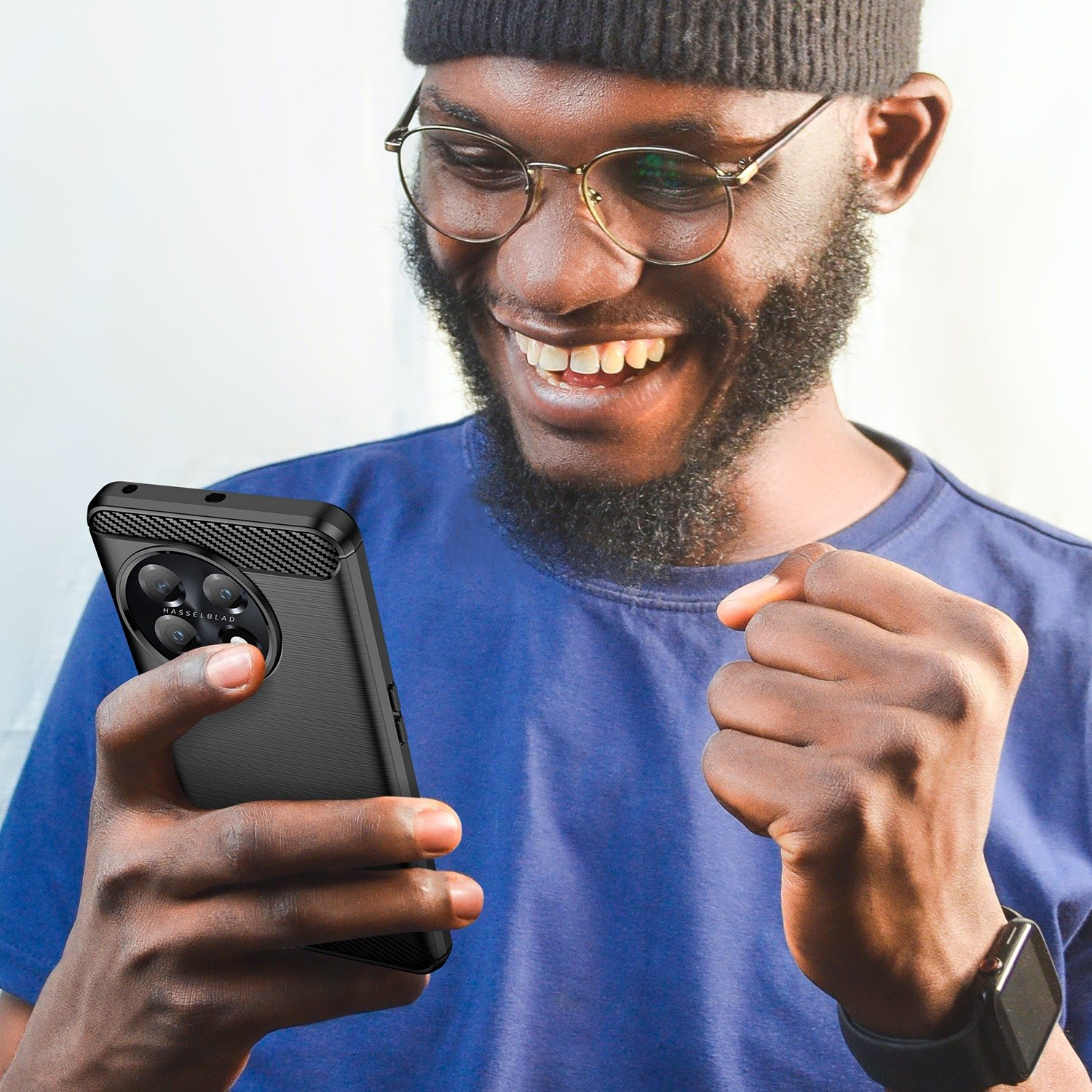 Un hombre sosteniendo un teléfono en una funda negra. Está sonriendo.