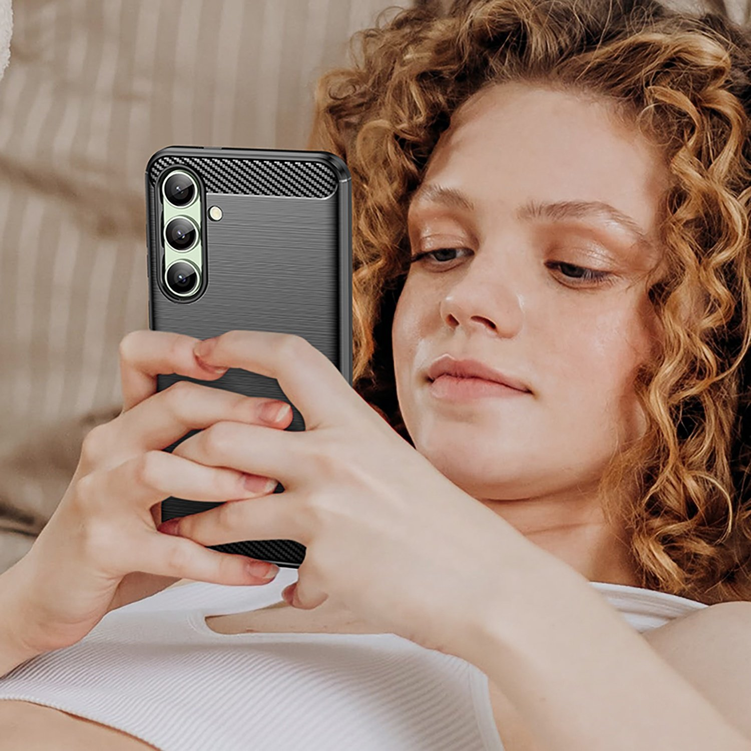 Mujer sosteniendo un teléfono con funda de fibra de carbono negra, mirando la pantalla.
