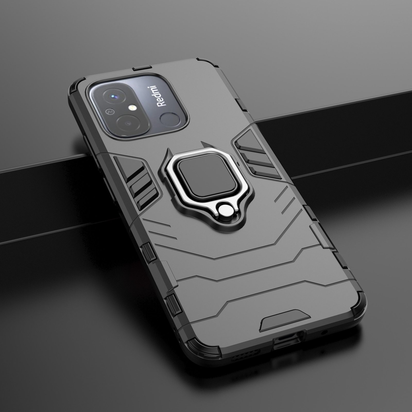 Funda gris para teléfono con soporte de anillo sobre una superficie oscura. La funda tiene un diseño robusto. Fondo negro.