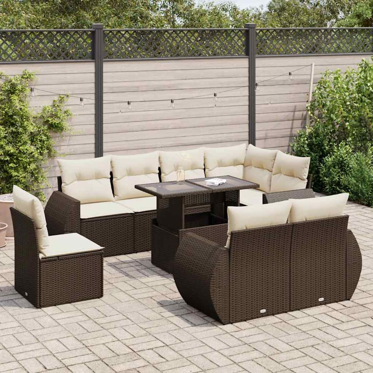 Set patio con tavolo. Mobili in vimini marrone, cuscini crema. Recinzione in legno.