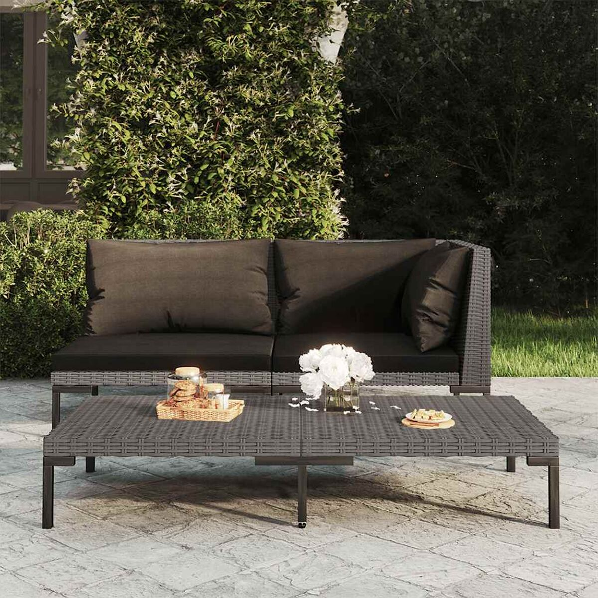 Outdoor-Sitzgruppe mit dunkelgrauem Couchtisch, Sofa und grünem Hintergrund.