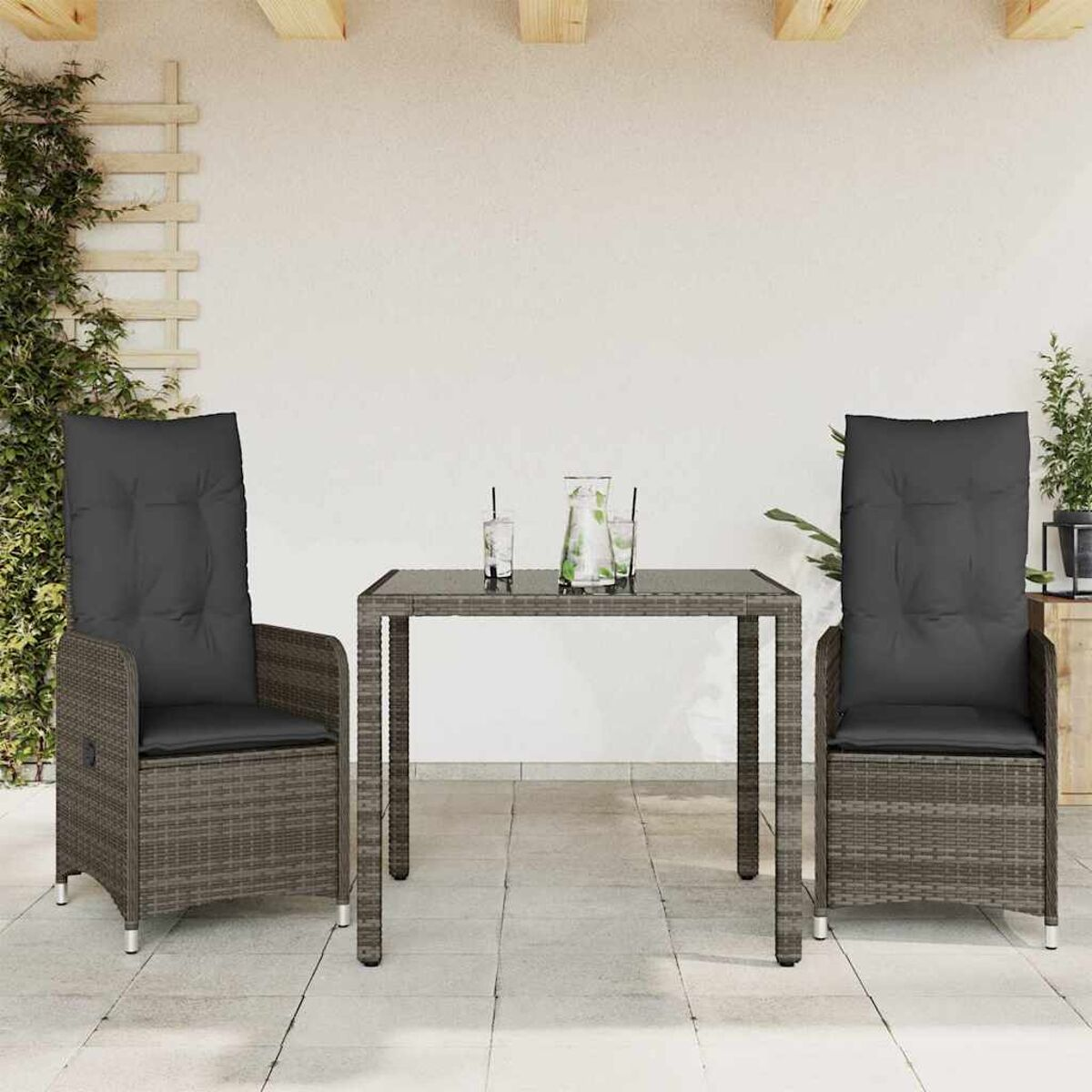 Terrassenmöbel: zwei Stühle mit hoher Rückenlehne, ein Tisch, Gläser mit Getränken. Graue Kissen und Korb.