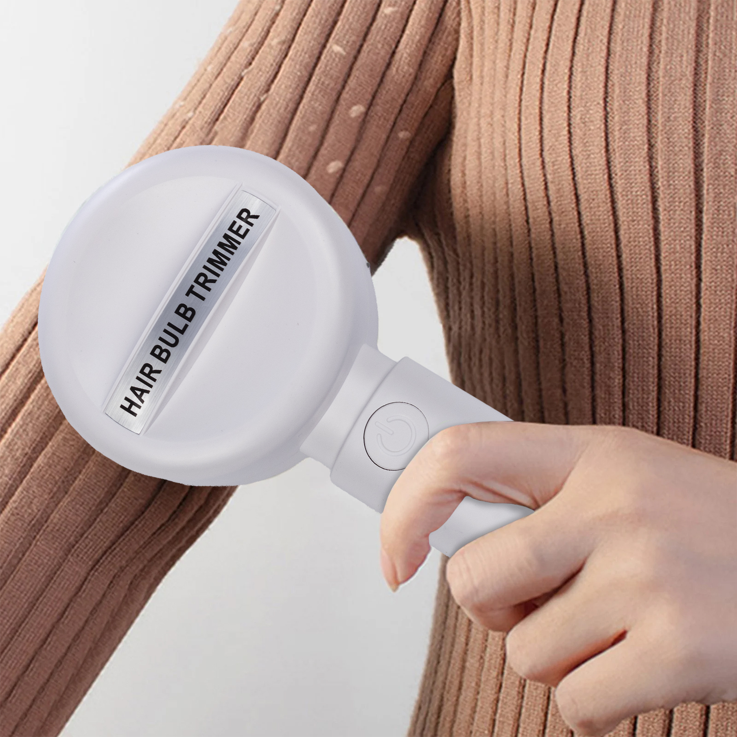Die Hand einer Person hält einen weißen Haarzwiebeltrimmer. Der Trimmer hat ein Etikett mit der Aufschrift "HAIR BULB TRIMMER".